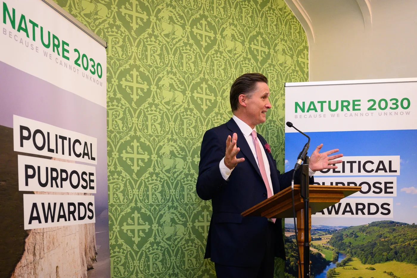 Charlie Maynard speaking at a lectern beside the Political Purpose Awards banners